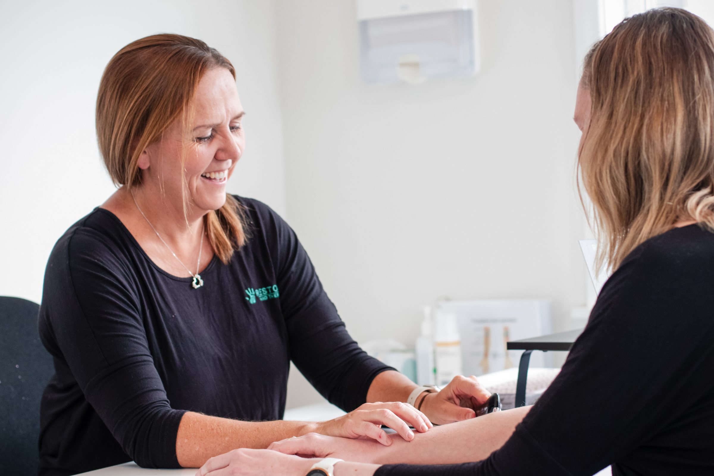 A Restore therapist assessing a patient's wrist movement at the clinic