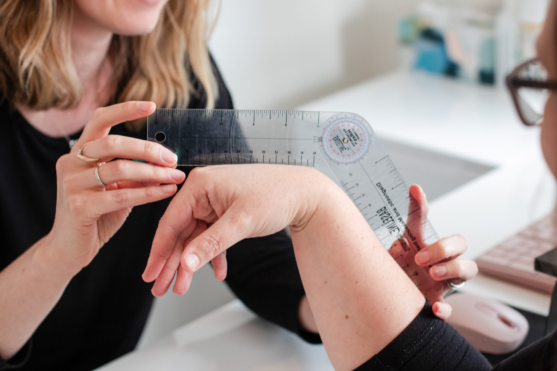 A Restore therapist measuring a patient's wrist movement with a goniometer