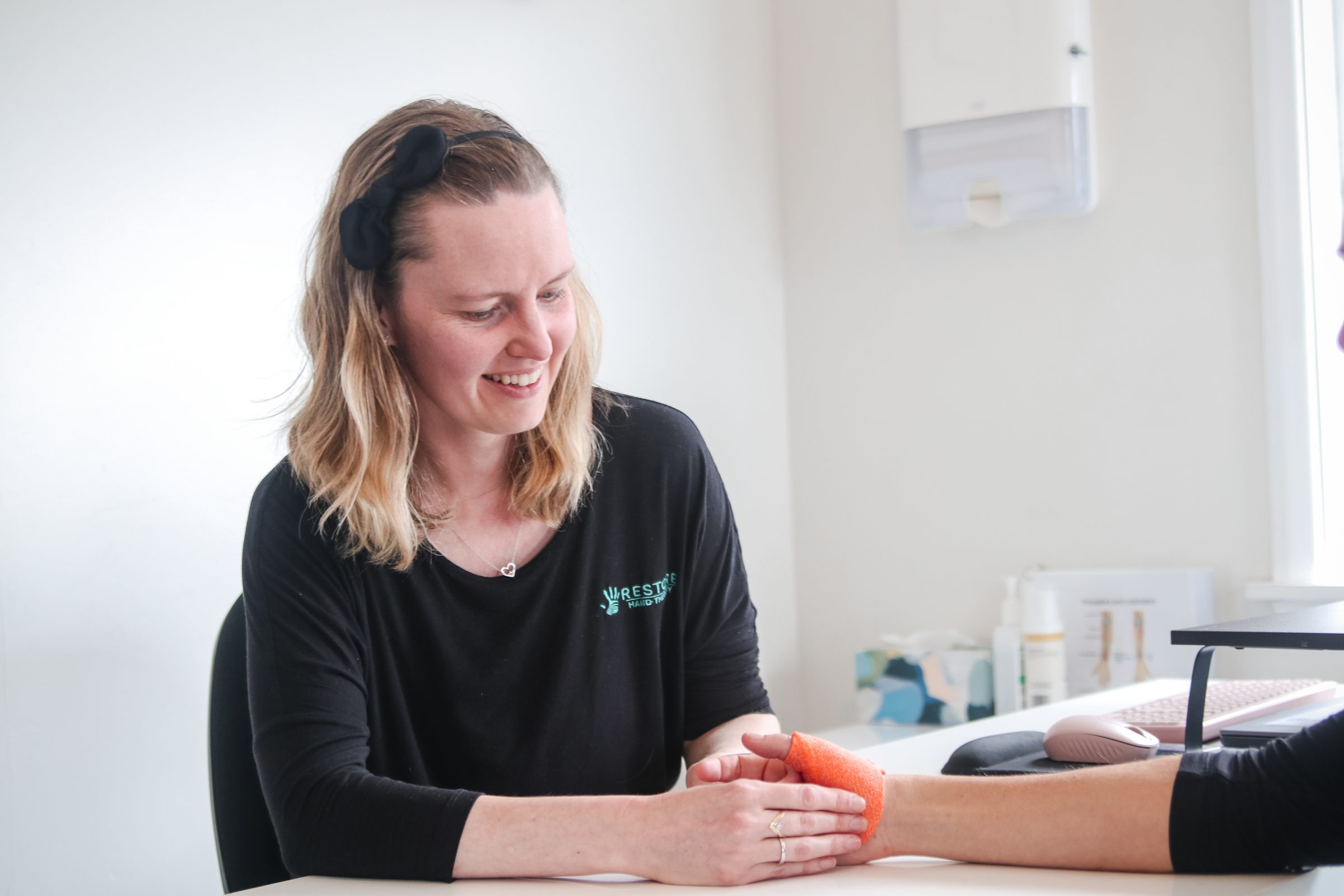 A Restore hand therapist smiling as she supports a patient's hand in a custom splint